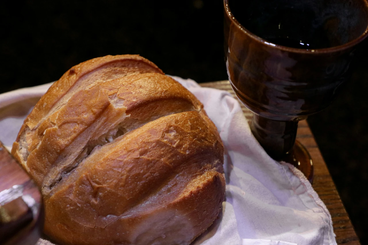 A chalice of wine and bread on a wooden table, symbolizing Holy Communion as a sacred Christian practice.