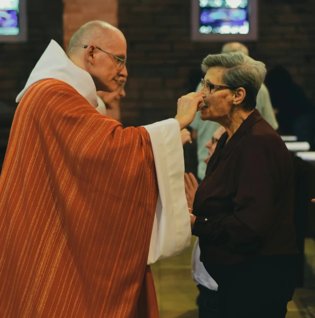 A priest offering bread during Holy Communion, a practice observed in various Christian traditions.